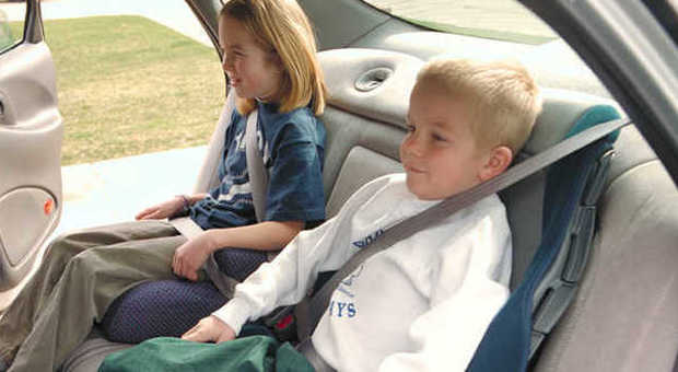 Due bambini in auto nei loro seggiolini